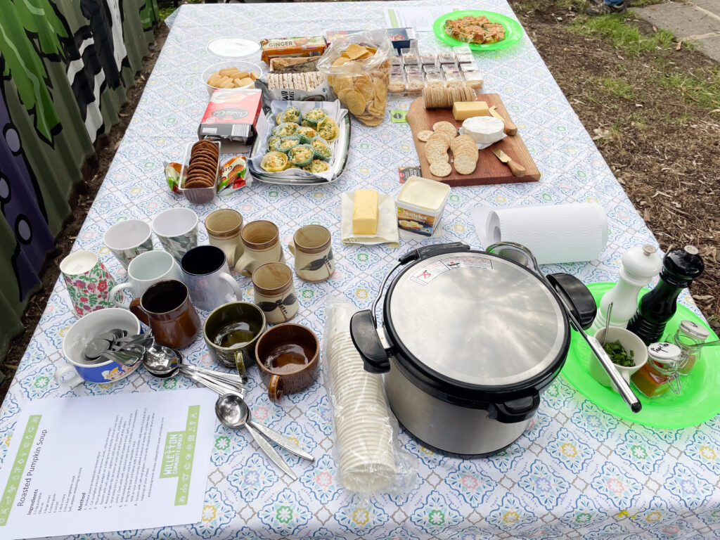 A table at a community celebration with pumpkin soup and cups